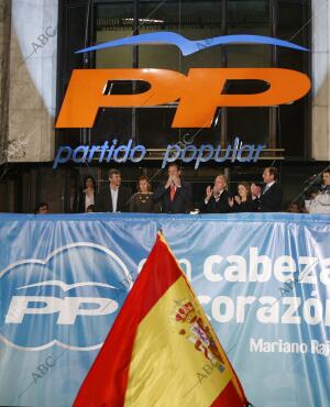 Mariano Rajoy y su equipo saludan desde el balcón de la sede del PP después de...