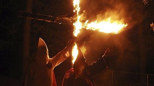 Varios miembros del Ku Klux Klan queman una cruz