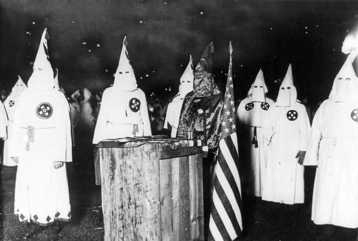 Miembros del Klan, junto a la bandera norteamericana