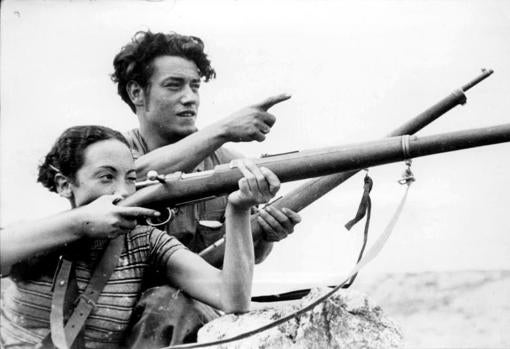 Un veterano de las milicias enseña a una miliciana el uso de un fusil