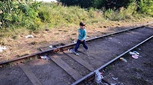 Siguiendo a su familia, un niño camina solo por las vías del tren cerca del pueblo de Roszke, en la frontera entre Serbia y Hungría