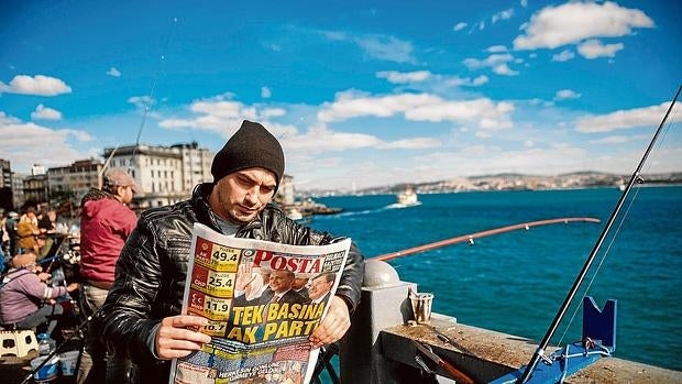 Un pescador lee la prensa en Estambul, con los resultados de las elecciones del domingo