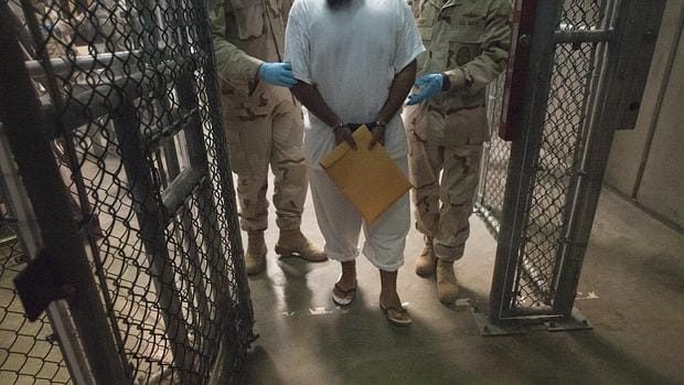 Un detenido entre dos militares estadounidenses, en Guantánamo en 2010