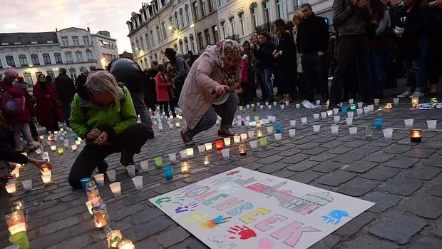 Un grupo de manifestantes del distrito de Molenbeek ponen velas en homenaje a las víctimas de París