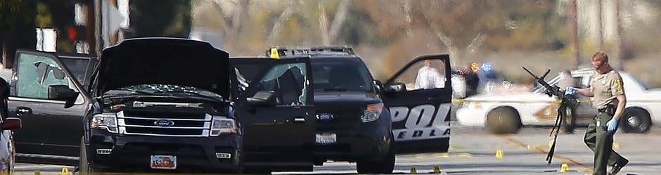 Un policía sostiene una de las armas encontradas en el lugar del tiroteo