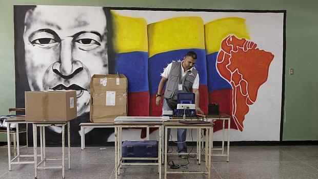 Un trabajador de la comisión electoral ante un mural de Chavez en un centro de voto