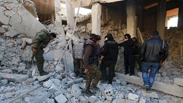 Combatientes kurdos inspeccionan el daño en un lugar golpeado por uno de los tres camiones bomba , en Tel Tamer