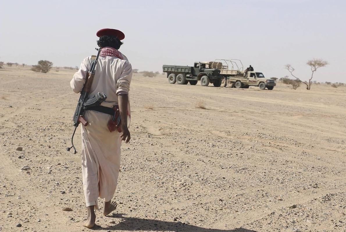 Un miembro de una milicia leal al gobierno depuesto se dirige hacia vehículos hutíes destruidos en una ofensiva