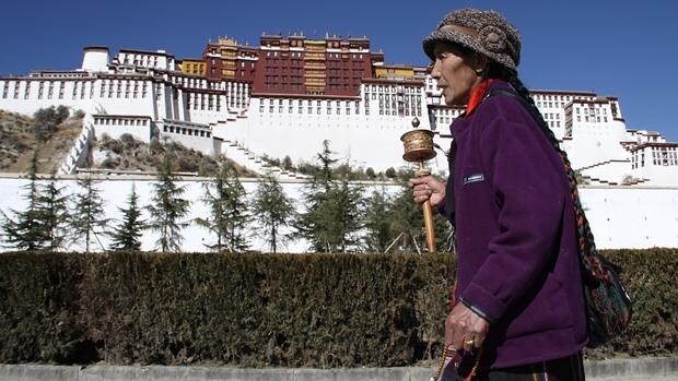 Dándole vueltas al molinillo de oraciones, una peregrina tibetana reza alrededor del Palacio de Potala, en Lhasa