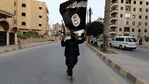 Un miembro de Estado Islámico pasea con su bandera por las calles de Al Raqqa