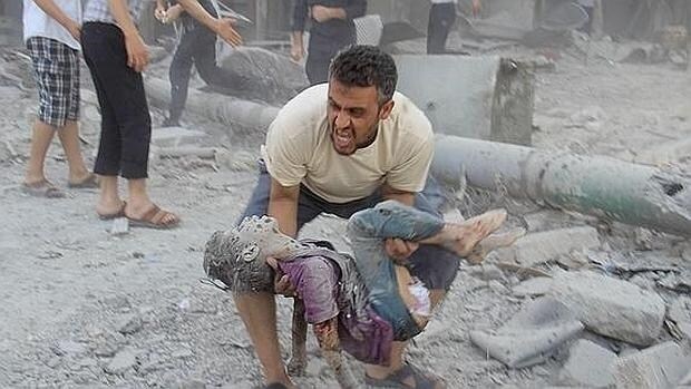 Un sirio recoge el cuerpo de su hijo en una calle de AlepO
