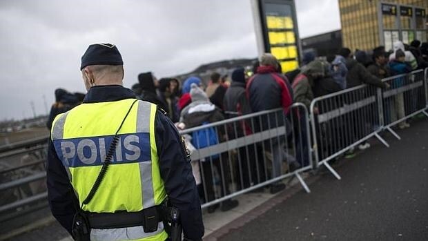 Un policía vigila a un grupo de refugiados en Suecia