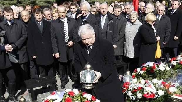 Jaroslaw Kaczynski (C), hermano del ex presidente Lech Kaczynski de Polonia, coloca una vela en las tumbas de las víctimas del accidente de avión del gobierno de 2010 en el cementerio militar de Powazki en Varsovia