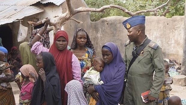Mujeres y niños liberados de manos de Boko Haram, junto a un militar nigeriano en Yola (Nigeria)