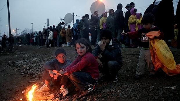 Refugiados alojados en el campamento de Idomeni (Grecia), esperan para pasar la línea del tren mientras y cruzar la frontera con la República de Macedonia