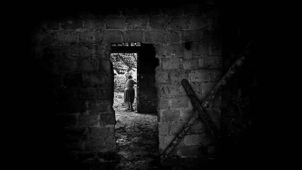 Una mujer de la comunidad de La Mona camina entre las ruinas de la casa parroquial