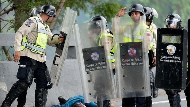 Un manifestante herido está tendido en el suelo junto a un grupo de policías durante la protesta contra Maduro del 11 de mayo en Caracas