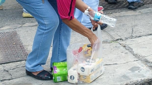 Una mujer organiza la compra de harina de maíz después de esperar horas de cola