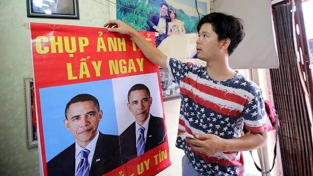 Un joven vietnamita cuelga un póster de Barack Obama