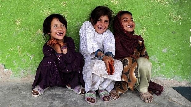 Niñas afganas sonríen en un refugio temporal en Kabul