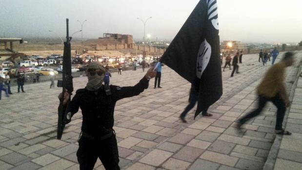 Un miembro de Daesh sostiene un arma y una bandera del grupo terrorista en Mosul