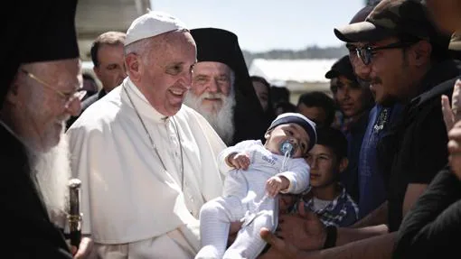 El Papa coge en brazos el bebé de uno de los refugiados