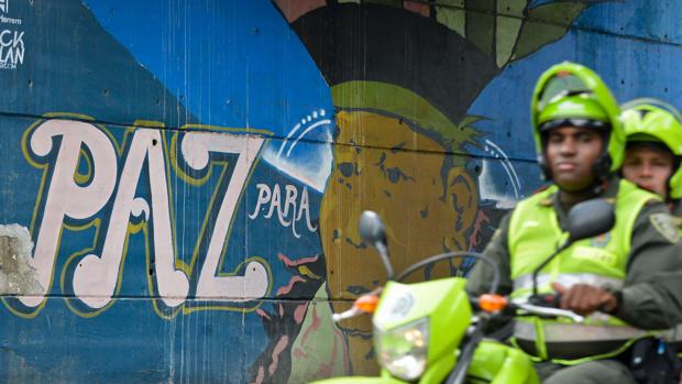 Unos motoristas pasan junto a un grafiti sobre la paz en Colombia, este miércoles en Cali