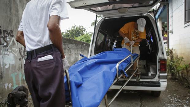 Trabajadores de una funeraria retiran un cadáver tras una operación policial en Pasay City, al sur de Manila, Filipinas, hoy, 5 de julio