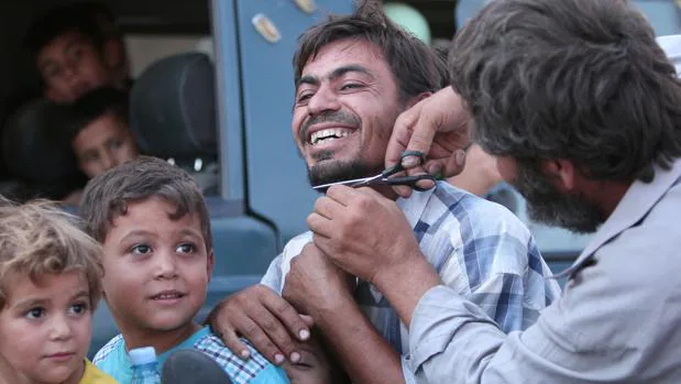 Un hombre afeita a un civil en público tras la liberación de la ciudad