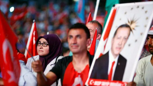 Seguidores de Erdogan, con la bandera turca, siguen su discurso desde una pantalla gigante en la plaza de Taksim, en Estambul, el pasado miércoles