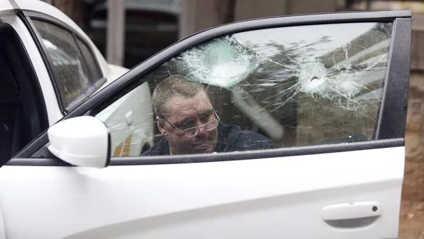 Un hombre arregla la ventana de uno de los coches patrulla dañados durante la protestas de Charlotte