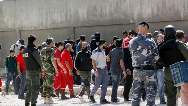 Soldados y Voluntarios de la Media Luna Roja Siria ayudan a rebeldes y familiares durante la evacuación del barrio asediado de Al Waer, en la ciudad de Homs