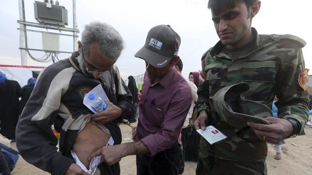 Un soldado iraquí observa las heridas de un desplazado por la guerra en el campo de refugiados de Mosul, capital de la provincia de Nínive