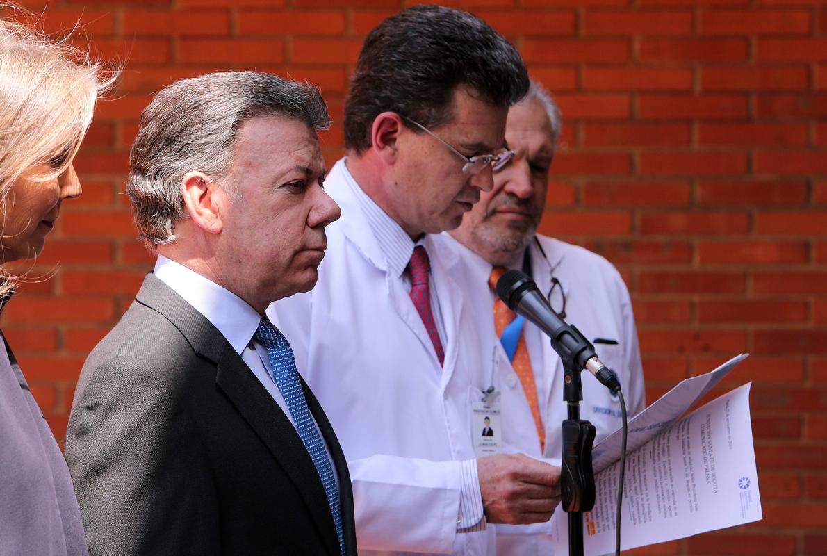 El presidente de Colombia Juan Manuel Santos escucha al médico Adolfo Llinás mientras lee los resultados médicos de los exámenes a los que fue sometido el presidente, en la clínica Santa Fe de Bogotá