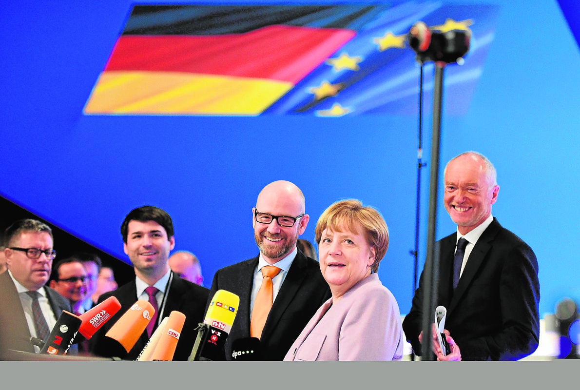 Merkel y otros miembros de la CDU conversan con la prensa en la víspera del congreso del partido, en Essen