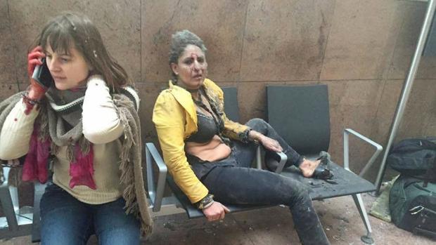 Foto que dio la vuelta al mundo que muestra a una mujer herida mirando como otra habla por su teléfono móvil después de las explosiones en el aeropuerto de Bruselas en Zaventem