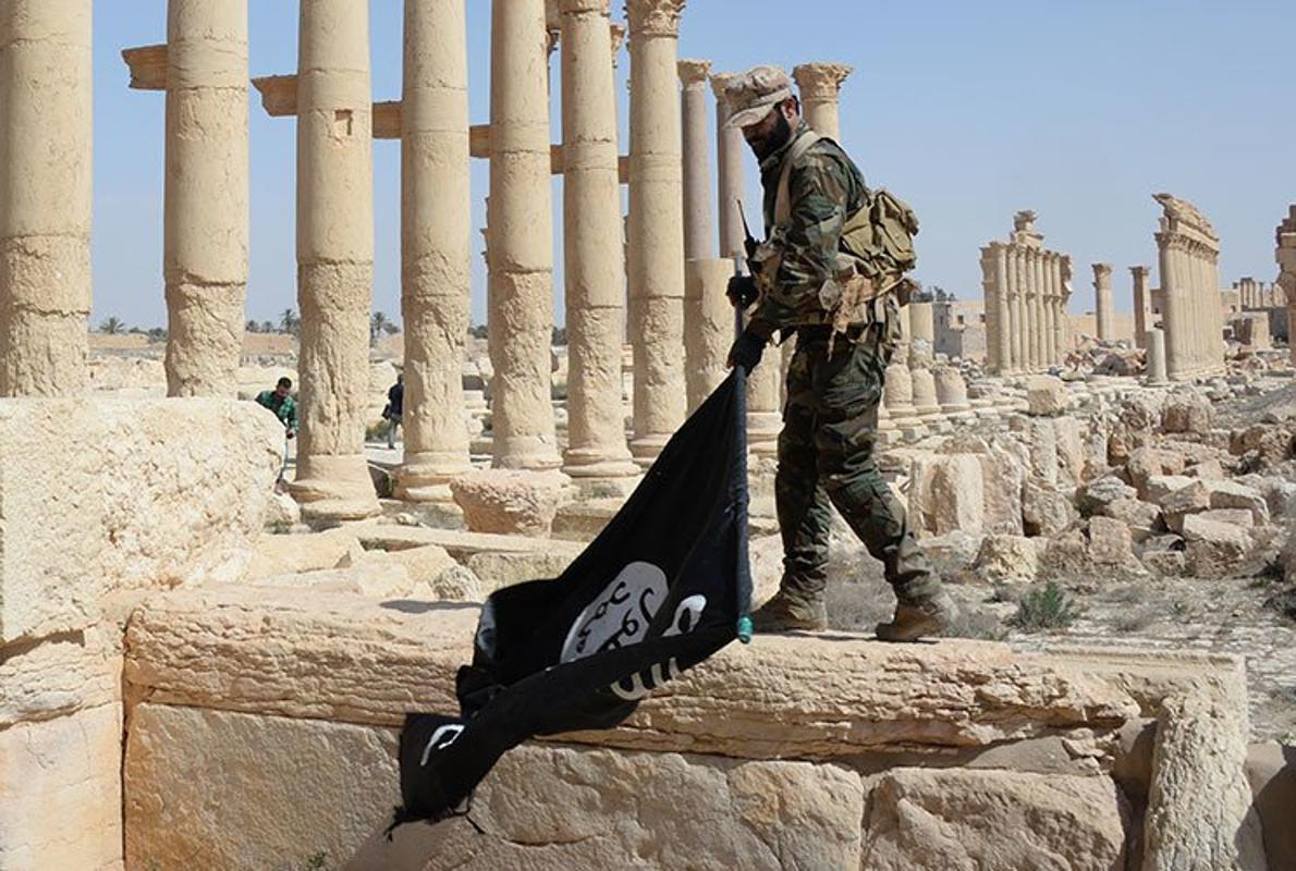 Imagen de archivo de un soldado sirio quita una bandera del «califato» en las ruinas