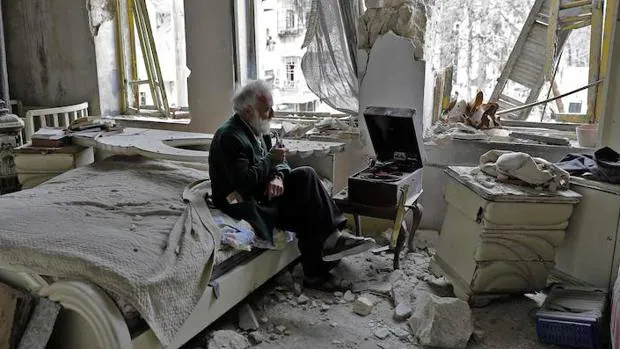 Un hombre fuma su pipa en su casa, en ruinas, de Alepo
