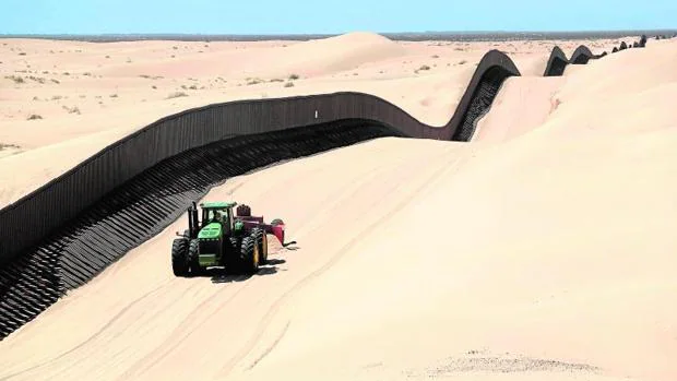 Una máquina quita la arena sobrante en la verja fronteriza con México, en California