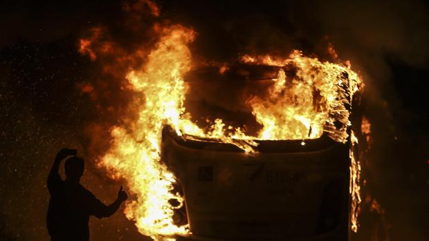 Un hombre hace un selfie ante un autobús quemado por manifestantes durante protestas en la huelga general
