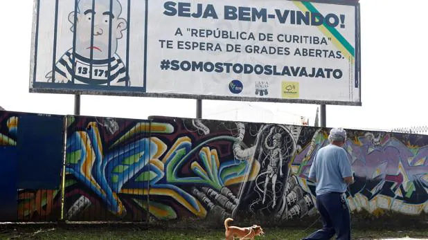 Un hombre pasa por delante de un cartel que refleja a Lula en la cárcel