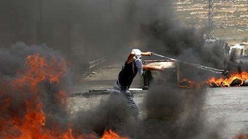 Un palestino lanza una piedra a tropas israelíes durante los disturbios por las celebraciones del día del Nakba en la ciudad cisjordana de Ramala (Palestina) hoy, 15 de mayo de 2017.