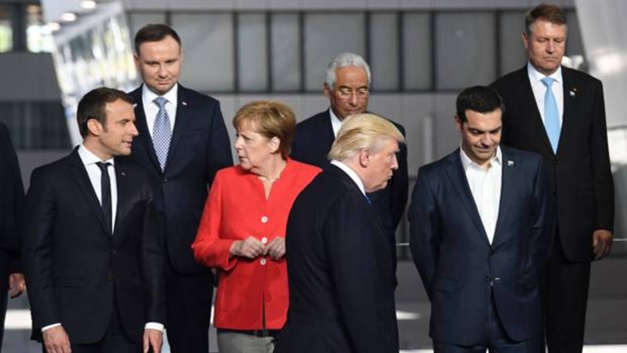 El presidente de los Estados Unidos, Emmanuel Macron, y la canciller alemana Angela Merkel (2ª I) hablan mientras el presidente estadounidense Donald Trump (C) llega junto al primer ministro griego, Alexis Tsipras, para una foto de familia durante la cumbre de la OTAN