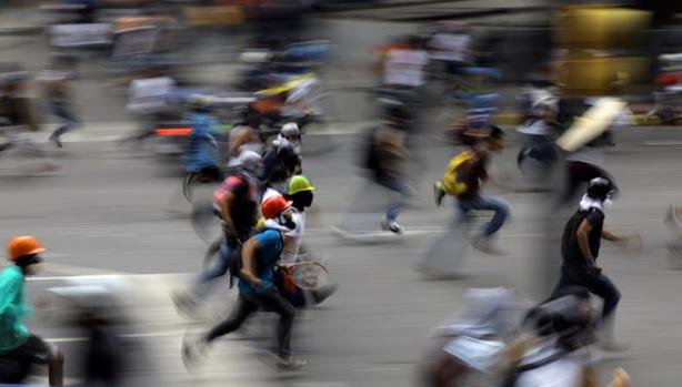 Manifestantes huyen de los gases lacrimógenos de las fuerzas antidisturbios durante una protesta antigubernamental este martes en Caracas