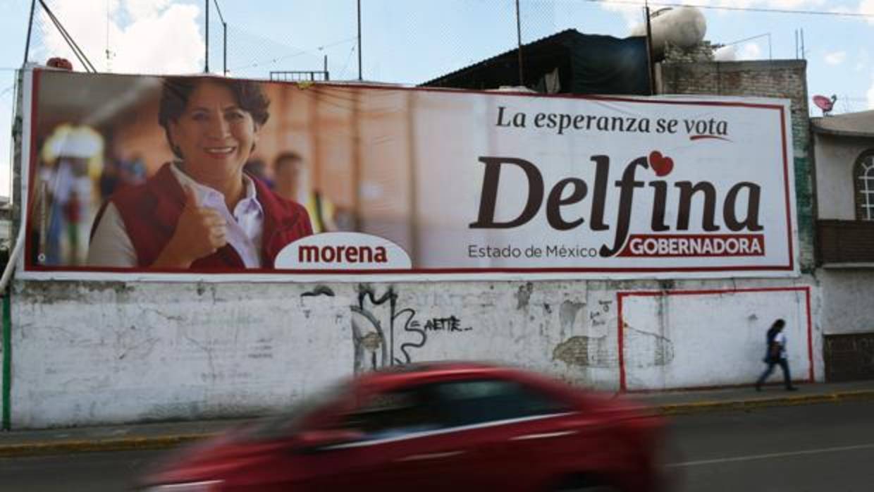 Un coche pasa por delante de un cartel publicitario que anuncia la candidatura de Delfina Gómez, del partido Morena