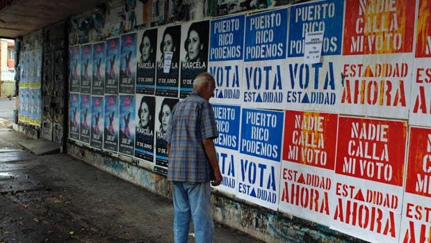 Un hombre lee carteles electorales en una calle de San Juan