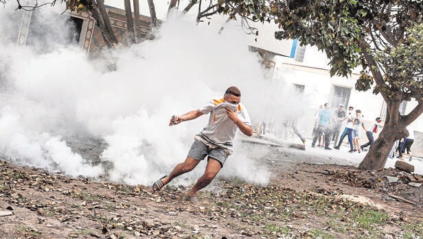 Un manifestante se protege del gas lacrimógeno lanzado por las Policía marroquí