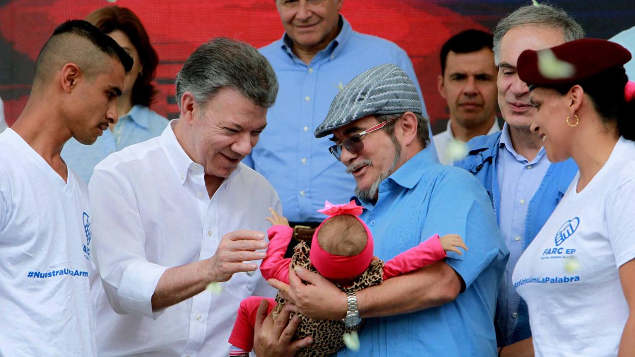 El presidente colombiano, Juan Manuel Santos, saluda a una bebé que sostiene el líder de las FARC, «Timochenko», en la ceremonia de dejación de armas en la zona veredal transitoria de normalización de Buenavista