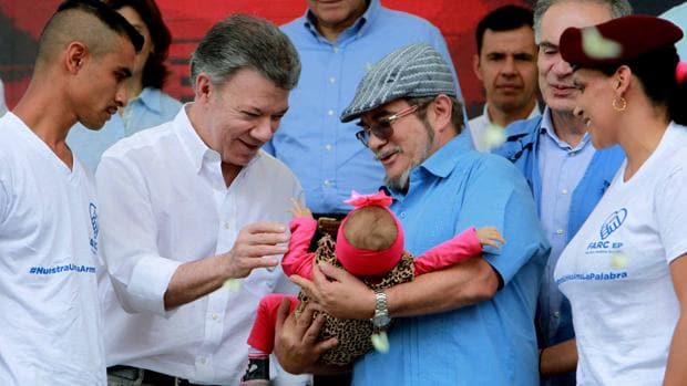 El presidente colombiano, Juan Manuel Santos, saluda a una bebé que sostiene el líder de las FARC, «Timochenko», en la ceremonia de dejación de armas en la zona veredal transitoria de normalización de Buenavista