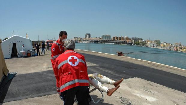 Trabajadores de la Cruz Roja ayudan a desembarcar a los 402 inmigrantes rescatados en el Mediterraáneo a su llegada al puerto de Brindisi (Italia)